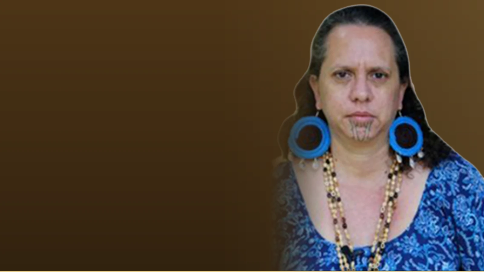 Ranu James, an Instructional Designer with traditional Māori facial markings and jewelry, poses for a portrait.